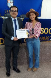 Zugner Regalado recibiendo su certificado de agradecimiento por parte de Rubí Molina, destacada estudiante de ECCO